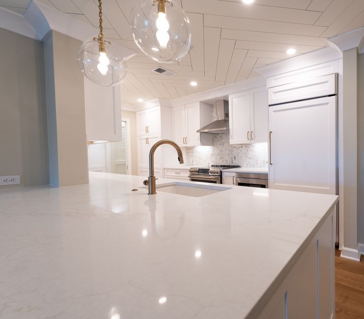 Sleek modern kitchen featuring white cabinets, marble island, and pendant lighting.