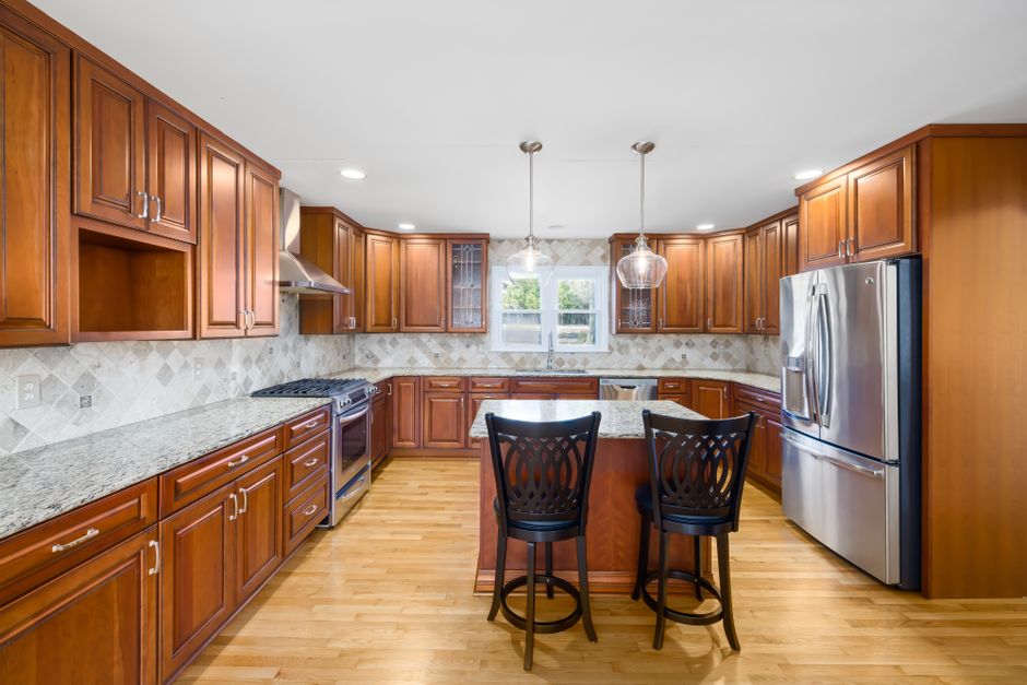 Bright kitchen design with wooden cabinets, island, and stainless steel appliances.