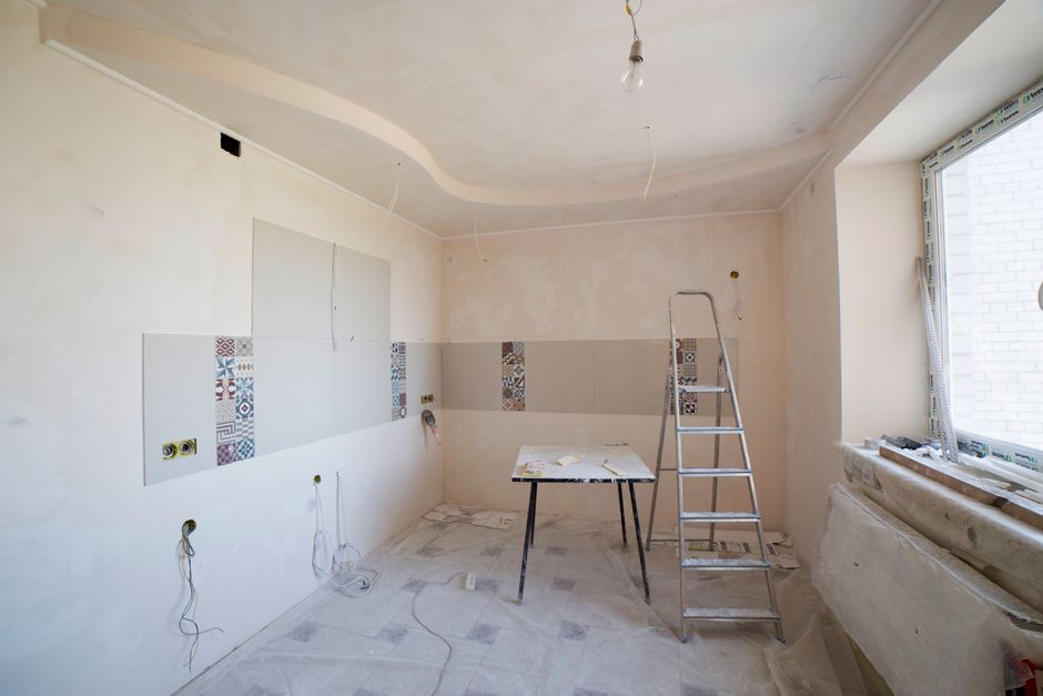 A kitchen under renovation with a ladder and tools on the floor.